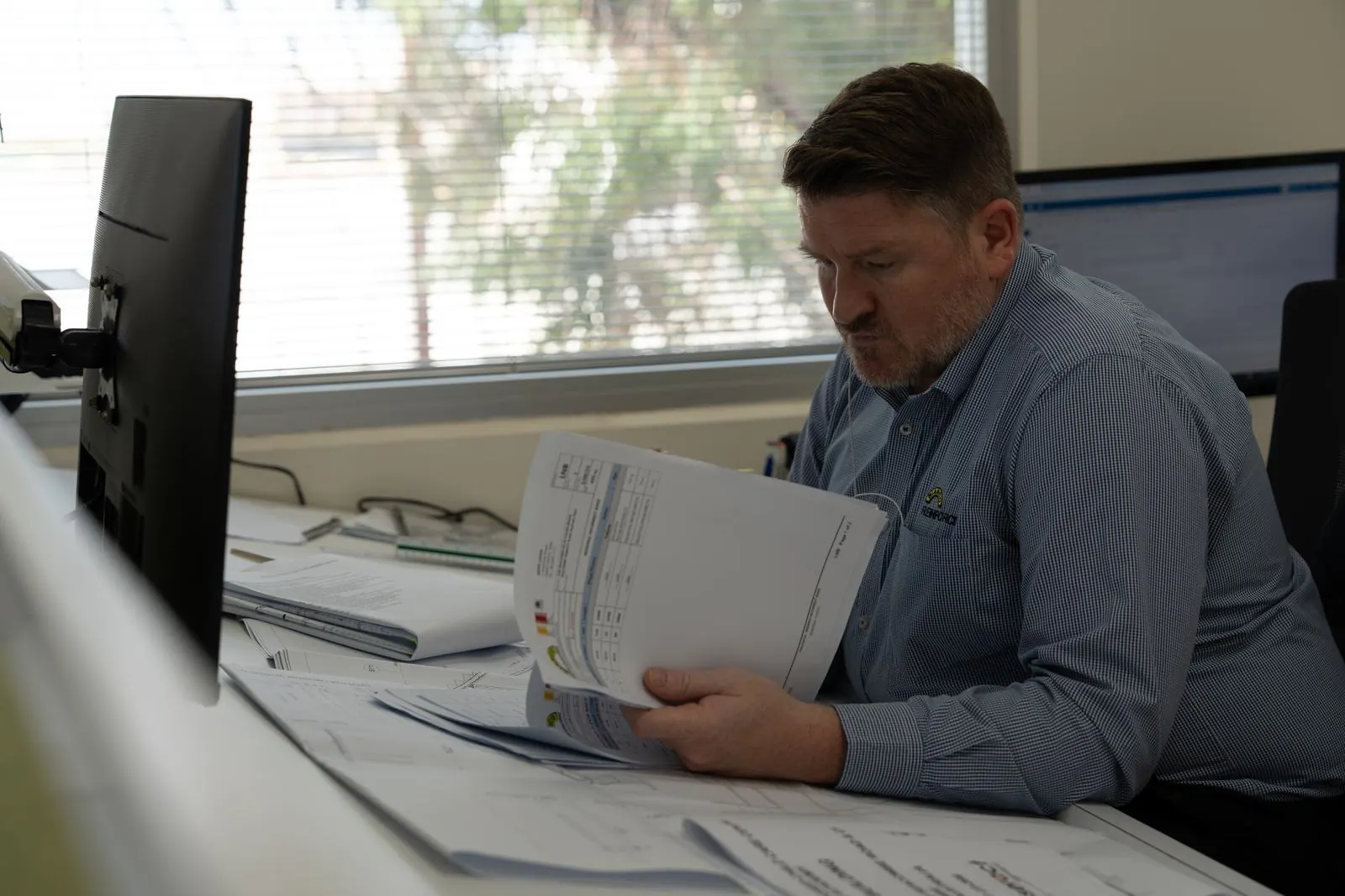 Estimator reviewing printed plans at his desk